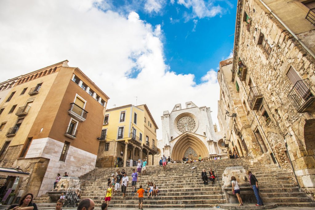 Tarragona, Spain - August 26, 2013: People walking and sitting on the stairs in front of Tarragona cathedral.