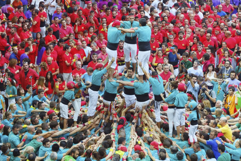 Tarragona, Spain - October 4, 2014: Members of the "Colla St.Pere y St.Pau", build a traditional human tower at the Tarragona during celebrations in Tarraco Square Sand castle contest, October 4, 2014, Tarragona, Spain. A perfect example of teamwork, union and brotherhood.